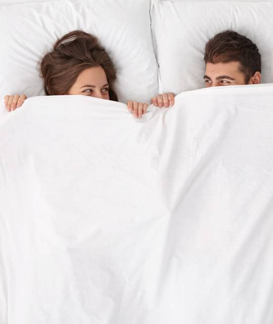 close-up-on-couple-lying-in-bed-under-white-blanket close-up-on-couple-lying-in-bed-under-white-blanket
